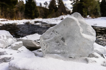Ice block on the snowy bank of the river