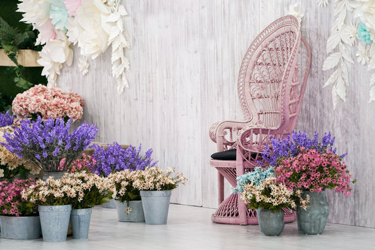 Luxury vintage bamboo chair front of white wood backdrop and many flower around.
