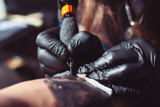Close Up Of The Tattoo Artist Hands Creating A Tattoo On A Girl's Arm
