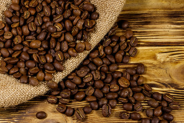 Roasted coffee beans on sackcloth on wooden table