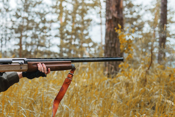 Hunting. Woman hunter holding a gun in the autumn forest