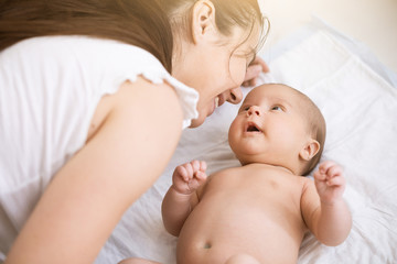 Portrait of happy mother and baby at home, smiling together. Family love, tender and happiness