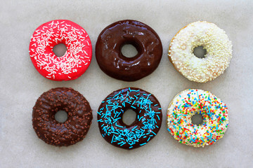Donuts of different colors on cardboard, top view
