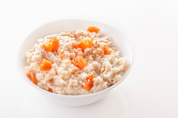 Oatmeal with pumpkin and nuts in a plate on a white background. Close-up. Copy space