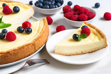 delicious sliced cheesecake with fresh berries and mint on stone background. close up