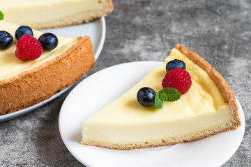 slice of cheesecake with fresh berries and mint on stone background. close up