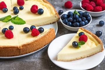Classic sliced New York cheesecake with fresh berries and mint on stone background, close up