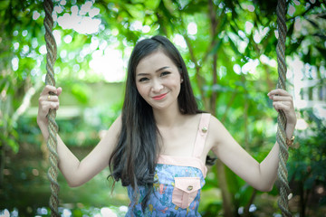 Asian pretty girl has relaxing with swing at Little Tree Garden cafe, Nakhon Pathom province, Thailand in the morning.