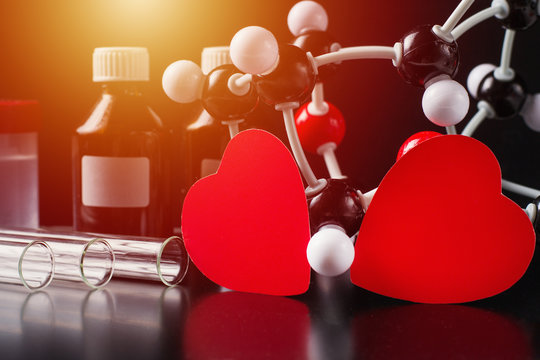 Two red paper hearts and molecular structure model on a black background. Love chemistry concept