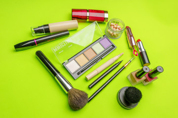 The composition of accessories, makeup cosmetics on a bright green background. Top view.   