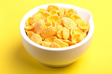 Crispy corn flakes in clay bowl on bright yellow background