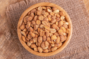 Roasted peanuts in wooden bowl on burlap napkin