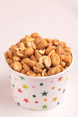 Roasted peanuts in paper cup on light marble background