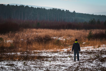 Young man standing landscape with snow and distant hills