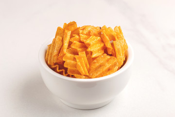 Crunchy corrugated potato chips in white bowl