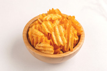 Crunchy corrugated potato chips in wooden bowl