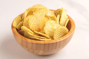 Crispy corrugated potato chips in wooden bowl