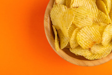 Crunchy corrugated potato chips in wooden bowl