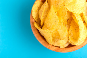Tasty crispy potato chips in wooden bowl