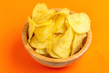 Tasty crispy potato chips in wooden bowl