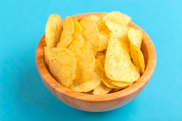Tasty crispy potato chips in wooden bowl