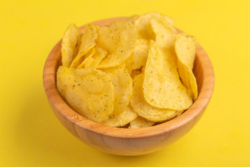 Tasty crunchy potato chips in wooden bowl