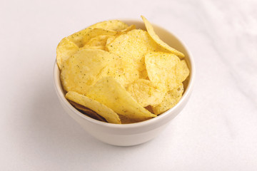 Tasty crispy potato chips in white bowl