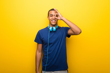 African american man with blue t-shirt on yellow background makes funny and crazy face emotion