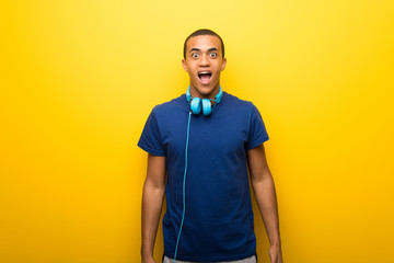 African american man with blue t-shirt on yellow background with surprise and shocked facial expression