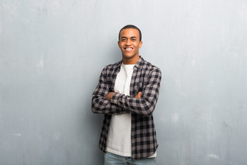Young african american man with checkered shirt keeping the arms crossed in frontal position