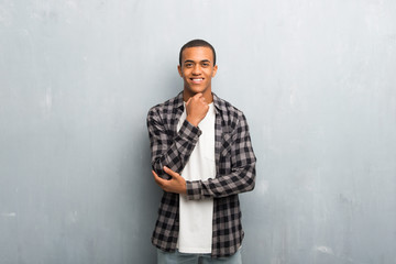 Obraz premium Young african american man with checkered shirt smiling and looking to the front with confident face