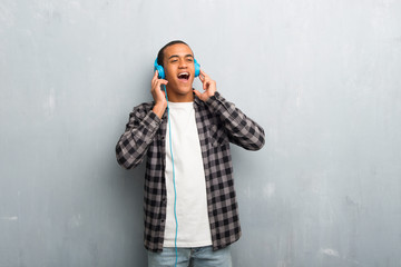Young african american man with checkered shirt listening to music with headphones