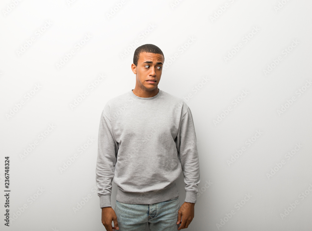 Wall mural african american man on white wall background is a little bit nervous and scared pressing the teeth