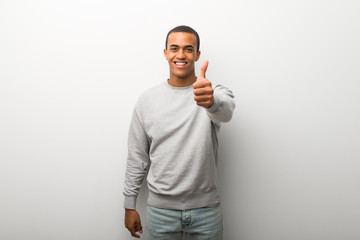 African american man on white wall background giving a thumbs up gesture because something good has happened