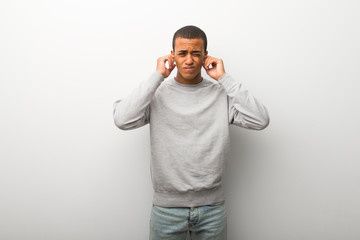 African american man on white wall background covering ears with hands. Frustrated expression