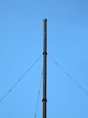 Obraz premium high industrial black metallic pipe on blue sky in sunny day, vintage construction diversity