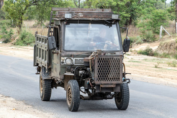 Chinese Manufactured tractor truck ride on road at countryside of Myanmar. Typical open-fronted battered lorry vehicle with air-cooled engine, Burma.