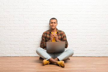 African american man sitting on the floor with his laptop scheming something