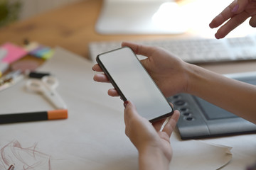 Stylish fashion designer using mobile phone in atelier.