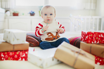 Happy little baby girl opening Christmas presents on her very first Christmas