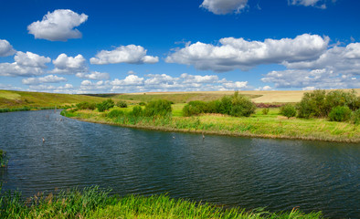 Sunny summer landscape with river,fields,green hills and beautiful clouds in blue sky