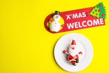 Small Santa Claus on white dish isolated on yellow background at Christmas day.Theme Christmas day background.