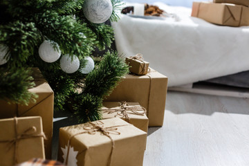 New Year's gifts under the Christmas tree. The gifts are packed in kraft paper and tied