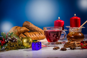 Traditional Christmas apple punch with cinnamon and honey on a table of candles on a light background