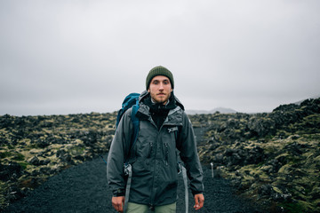 Portrait of proud and brave young adventurer hiker, explorer handsome man with trekking backpack...