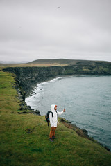 Fototapeta na wymiar Millennial or hipster adventure seeking man, urban nomad from generation z explores iceland rural countryside. Makes selfie or video chat for social media followers, share emotions and experiences