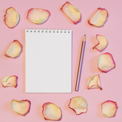 Notebook and pencil with dried cream rose petals on pink pastel