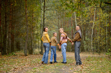 Naklejka na ściany i meble Portrait of family of four walking in autumn forest