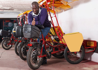 Fototapeta na wymiar African-American man bikecab driver standing near rickshaw cycle