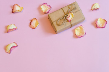 Gift box wrapping in kraft paper with dried cream rose petals on